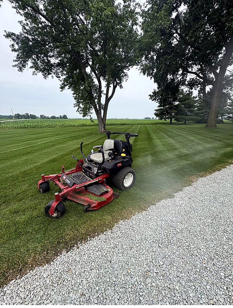 Riding mower on a striped lawn by a cornfield